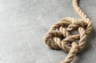Gri arka planda düğümlenmiş kalın ip. Metin için yer