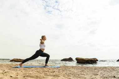 Kız doğada yoga yapıyor, deniz kenarında.