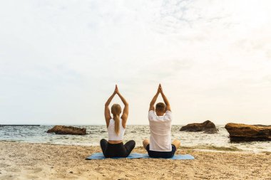 Bir çift deniz kıyısında meditasyon yapıyor.