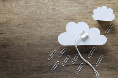 Beyaz USB kablolu beyaz kağıt bulutlar ve tahta arka planda metal ataçlar, metin için yer