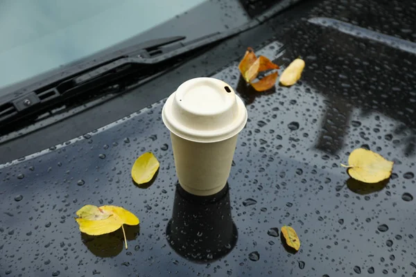 A car on the background of an autumn rainy park with coffee on the hood