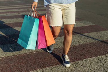 Şehirde renkli alışveriş çantalı bir kadın var.