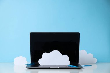 Mavi zemin üzerinde kağıt bulutlar olan dizüstü bilgisayar