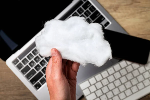 stock image A white cloud made of cotton wool in the hand on the background of a laptop