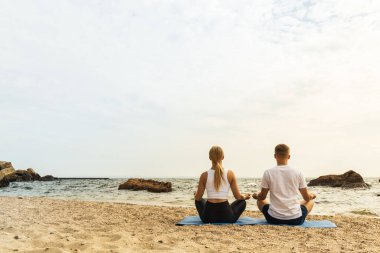 Bir çift deniz kıyısında meditasyon yapıyor.