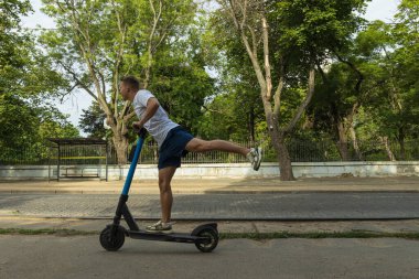 Parkta elektrikli scooter kullanan bir adam.