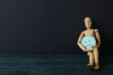 Koyu mavi arka planda üzgün emojisi olan ahşap adam, metin için boşluk