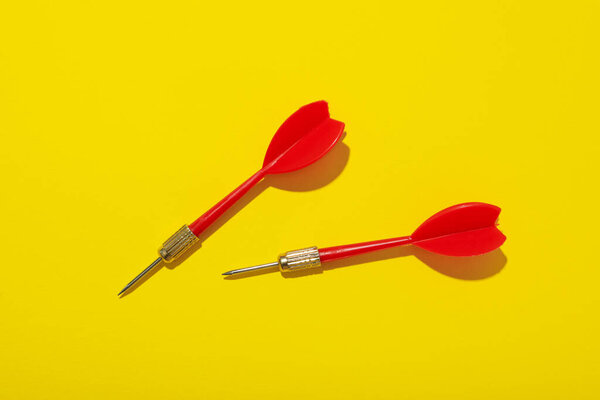 Дартс для попадания в цель на желтом фоне.