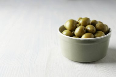 Beyaz ahşap arka planda zeytinler, metin için boşluk