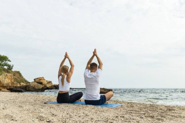 Bir çift deniz kıyısında meditasyon yapıyor.