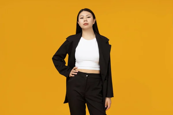 stock image A serious Asian girl dressed in a classic, strict style, on a yellow background