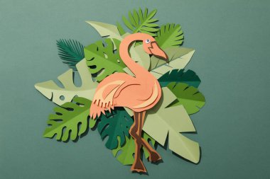 Yeşil arka planda kağıt yeşili tropikal yapraklar. Bir flamingo kuşuyla.