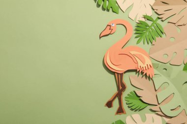 Yeşil arka planda kağıt yeşili tropikal yapraklar. Bir flamingo kuşuyla.