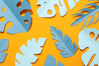 Sarı arka planda kağıt mavisi tropikal yapraklar.