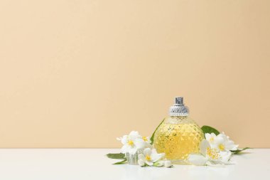 Yasemin çiçekleri ve bej arka planda parfüm şişesi, metin için boşluk