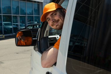 Gülümseyen bir kurye arabanın camından dışarı bakar.