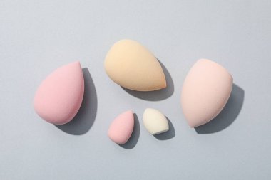 Gri arkaplanda kozmetik süngerler, üst görünüm