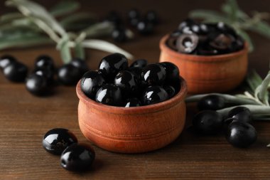 Ahşap arka planda kapta zeytinler, yakın plan