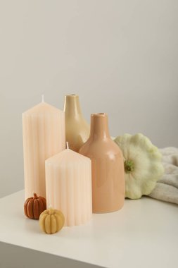 Mumlar, vazolar ve kabaklar beyaz masada, arka planda.