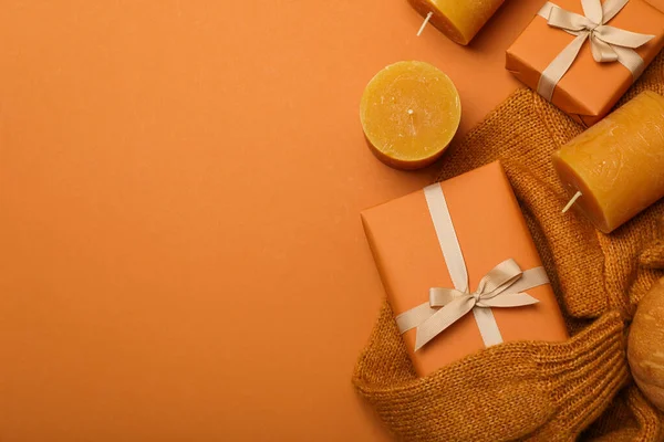 Candles and boxes on sweater on orange background, space for text