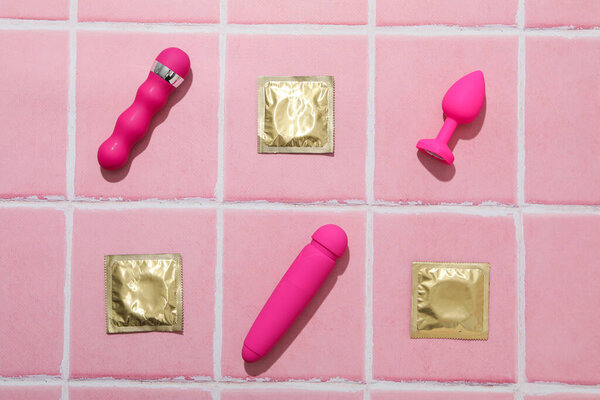 Condoms, butt plug and vibrators on a pink background