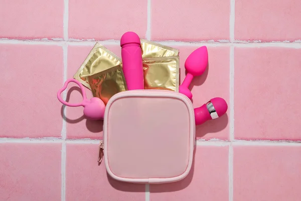 ピンクの背景にコンドームと性のおもちゃが付いているピンクのハンドバッグ — ストック写真