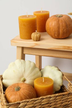 Mumlar ve balkabakları beyaz arka plandaki ahşap raflarda kutuda