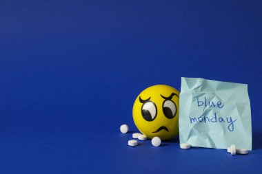 Not: Mavi Pazartesi, haplar ve mavi arka planda üzgün emoji, metin için boşluk