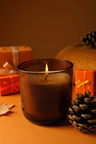 Candle, cones and gift boxes on orange background