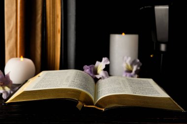 Koyu arkaplanda açık kitap, mum ve çiçekler