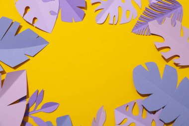 Sarı arka planda kağıt mor ve pembe tropikal yapraklar.