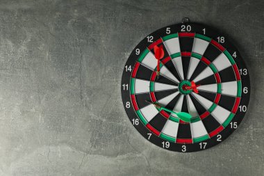 Dartlar hedefi gri arka planda kablolarla vuruyor.