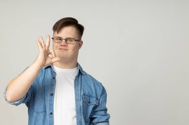 Gözlüklü, kot pantolonlu ve kameraya poz veren, beyin felçli gülümseyen genç bir adam. Dünya Genetik Hastalıklar Günü konsepti, metin için yer