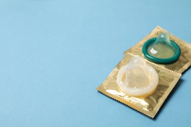 Mavi arkaplanda paketli olmayan prezervatif, metin için boşluk