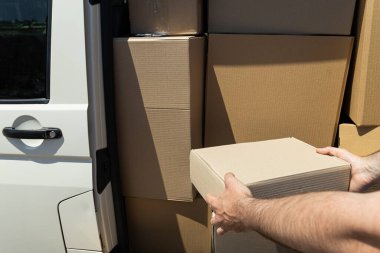 Elinde bir paket olan bir kutu, arabaya yükleniyor..