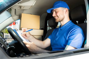 Gülümseyen bir kurye paketleri arabayla taşır.