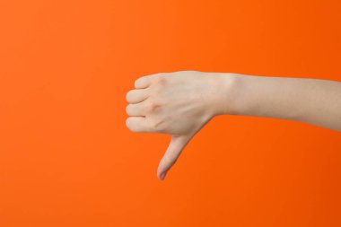 Turuncu arka planda parmağını gösteren bir kadın el.