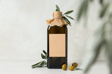 Gri arka planda zeytin yağı şişesi ve zeytin