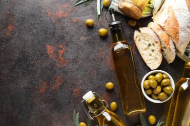 Şişeler dolusu zeytinyağı, zeytin ve gri arka planda dilimler, metin için boşluk