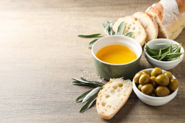 Zeytinyağı, zeytin ve ekmek dilimleri ahşap zemin üzerinde, metin için boşluk