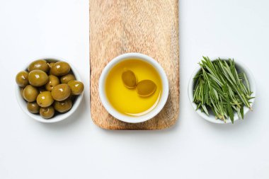 Beyaz arka planda zeytin dalları, yağ ve zeytin kaseleri, üst görünüm