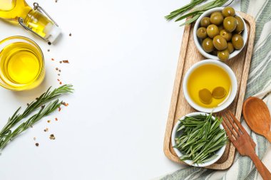 Kâselerde zeytin dalları, yağ ve zeytin, beyaz arka planda havlu, metin için yer