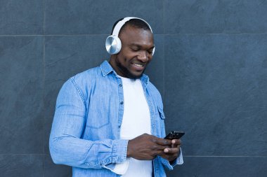 Tarz sahibi, genç bir Afro-Amerikan adam kulaklıkla müzik dinliyor.