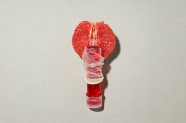 Bir şişe kayganlaştırıcının üzerindeki prezervatif sulu bir greyfurtun yanında.