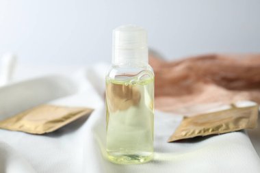 Şeffaf bir şişede kayganlaştırıcı ve arka planda kondomlar.