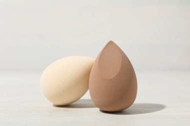 Hafif ahşap arka planda kozmetik süngerler, kapatın.