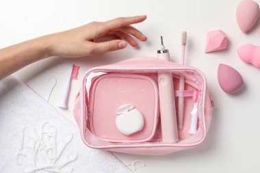 Elektrikli diş fırçası, kozmetik süngerler ve beyaz arka planda kadın eli.