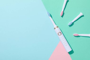 Mavi ve yeşil arkaplanda elektrikli diş fırçaları, metin için boşluk