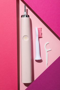 Pembe arka planda elektrikli diş fırçası, üst görünüm