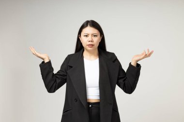 Gri arka planda klasik, sade giyinmiş ciddi bir Asyalı kız.